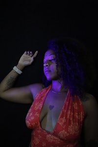 a woman in a red dress posing in front of a purple background