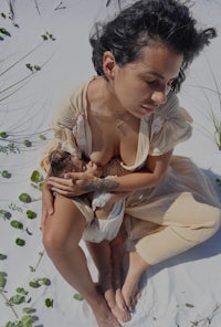 a woman is holding a baby in the sand